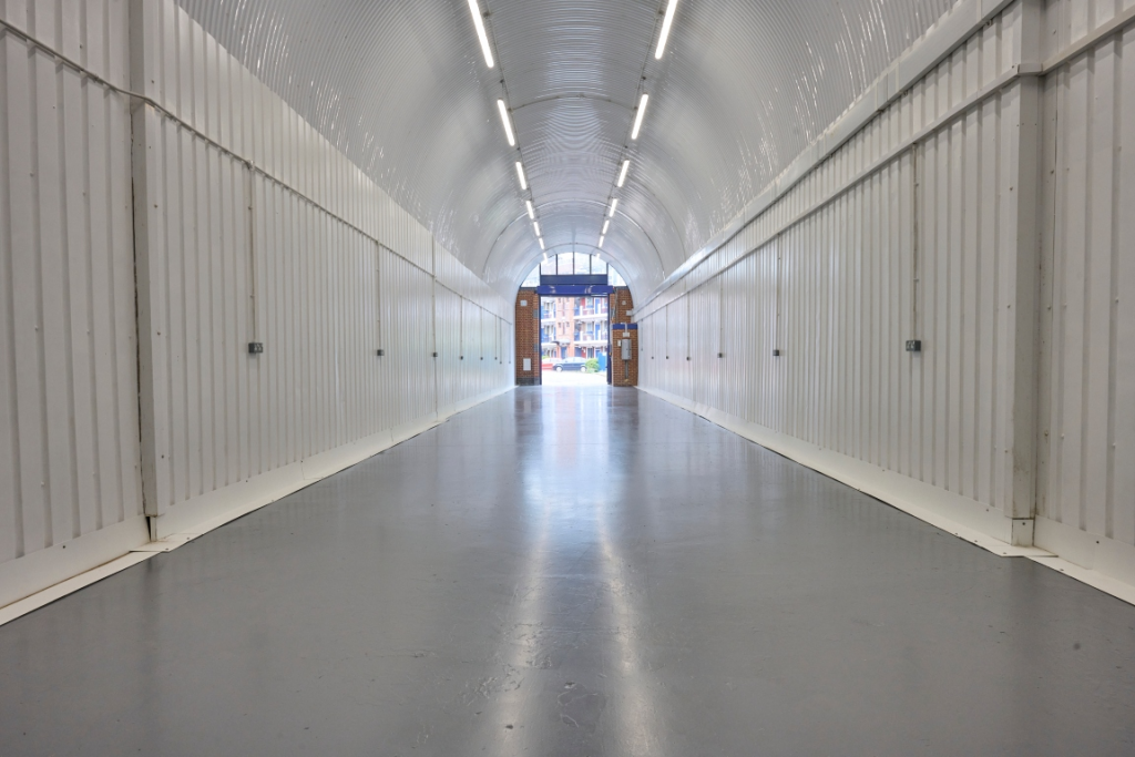 An empty arch with lining, facing the front electric roller shutter entrance, which is open.