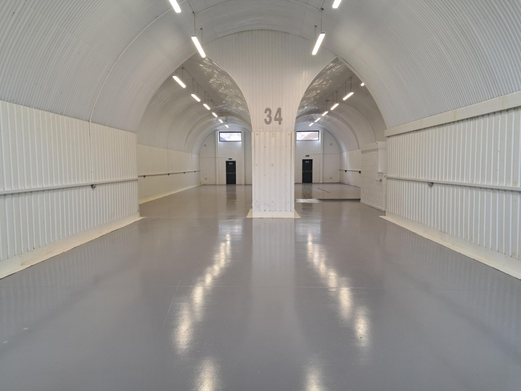An empty arch with white lining and a WC cubicle to the front.