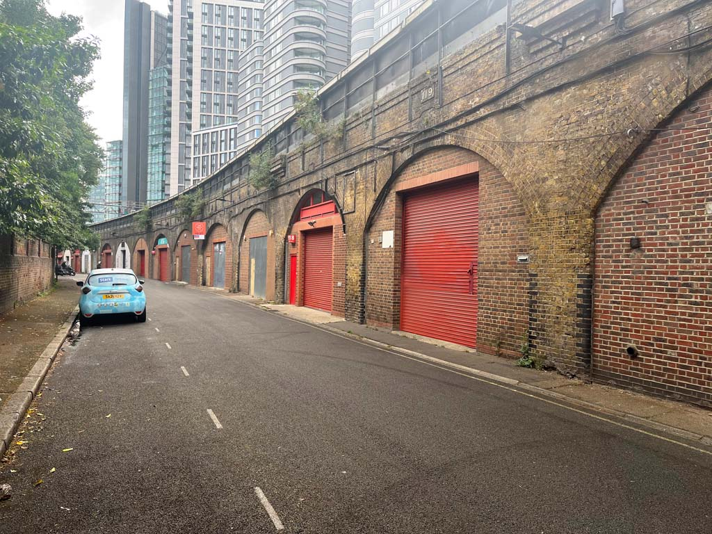 An estate, with multiple arches next to each other. The arches have closed electric roller shutter entrances.