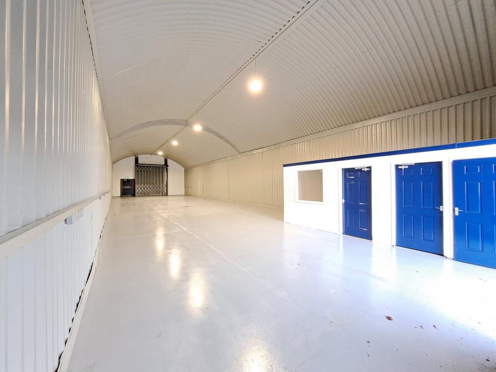 An empty arch with white lining and a WC cubicle to the front.