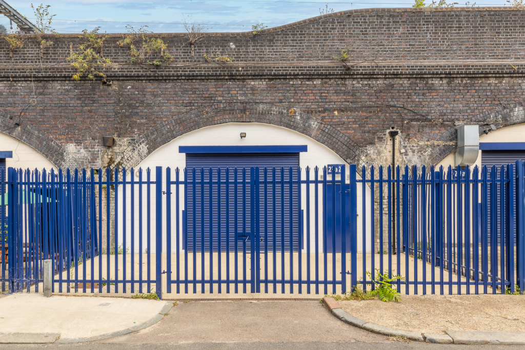The front of an arch with a closed electric roller shutter entrance big enough for vehicle access.