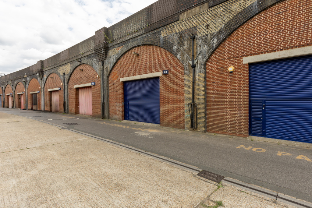 An estate, with multiple arches next to each other. The arches have closed electric roller shutter entrances.