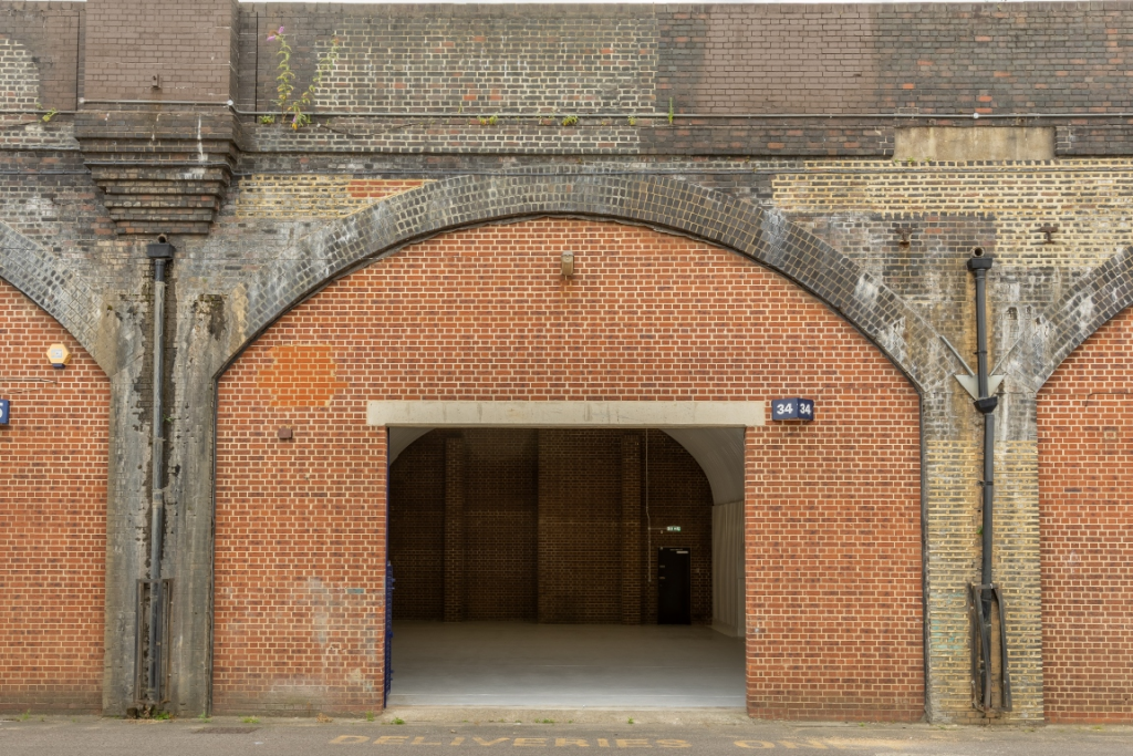 The front of an arch with an open electric roller shutter entrance big enough for vehicle access.