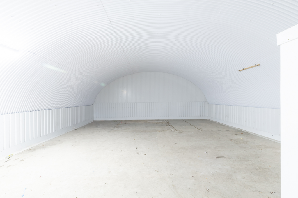 An empty arch with white lining and a WC cubicle to the front.