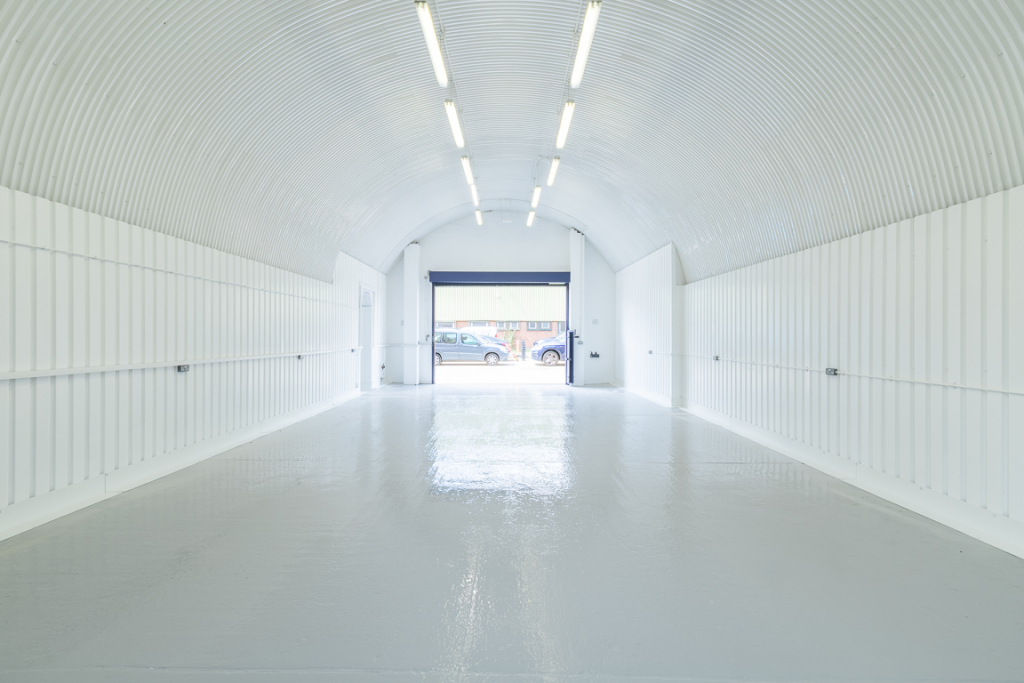 An empty arch with white lining, facing the front electric roller shutter entrance, which is open.