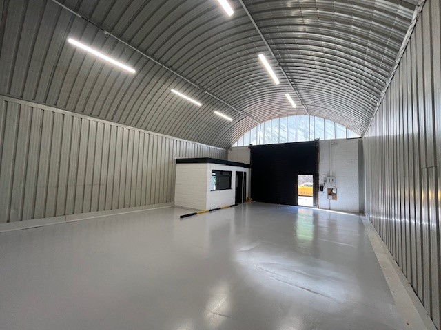 An empty arch with white lining and a WC cubicle to the front.