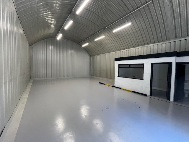 An empty arch with white lining and a WC cubicle to the front.