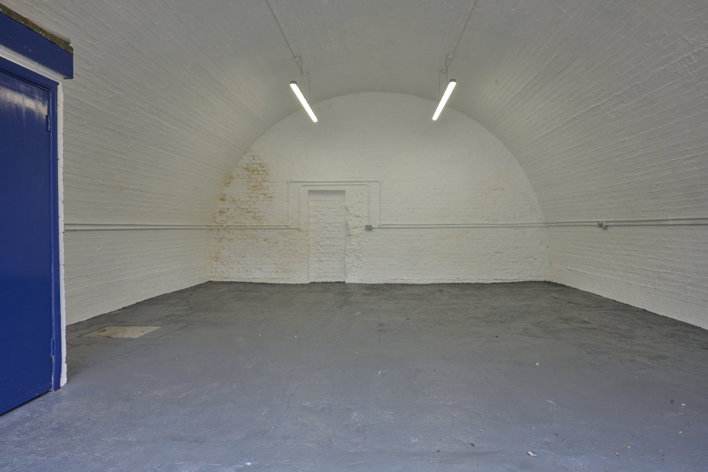 An empty arch with white lining and a WC cubicle to the front.