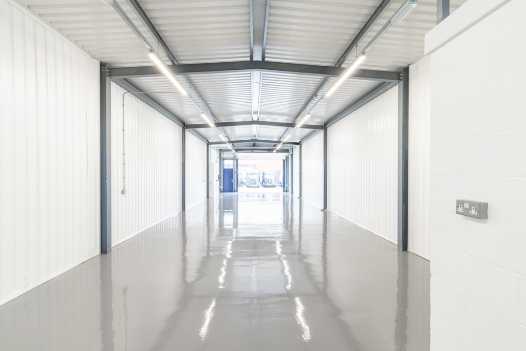 An empty arch with white lining, facing the front electric roller shutter entrance, which is open.