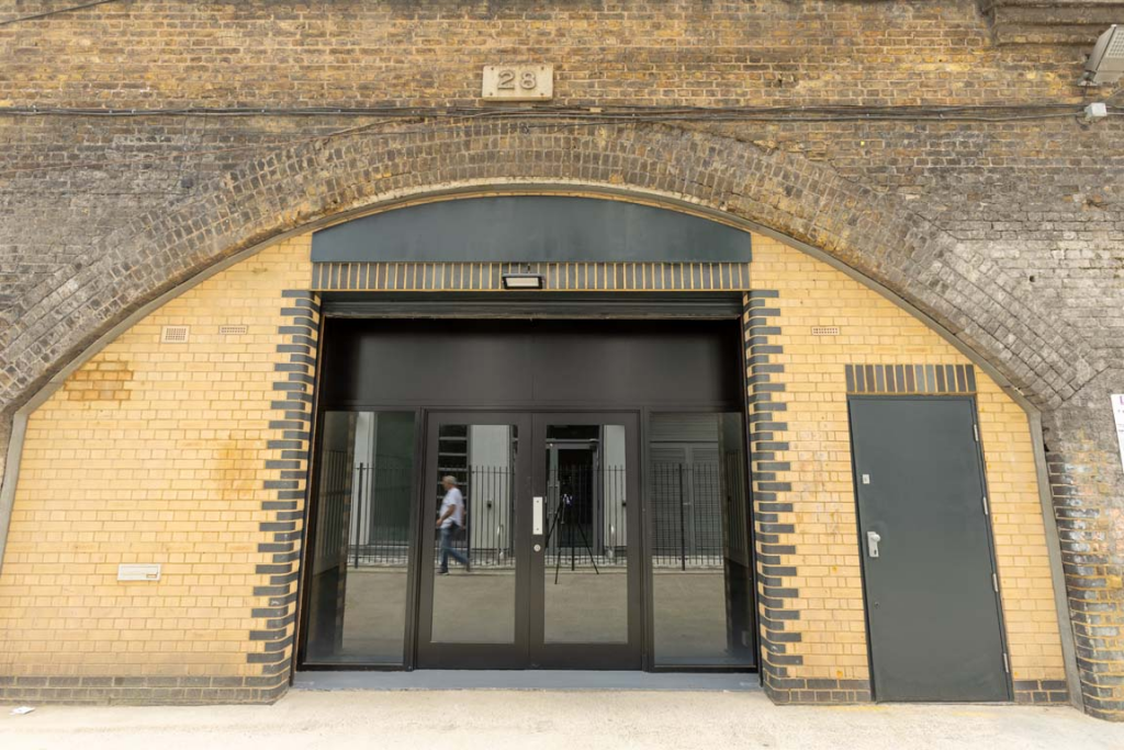 The front of an arch, with high level glazing, an open electric roller shutter entrance big enough for vehicle access, and a pedestrian door.