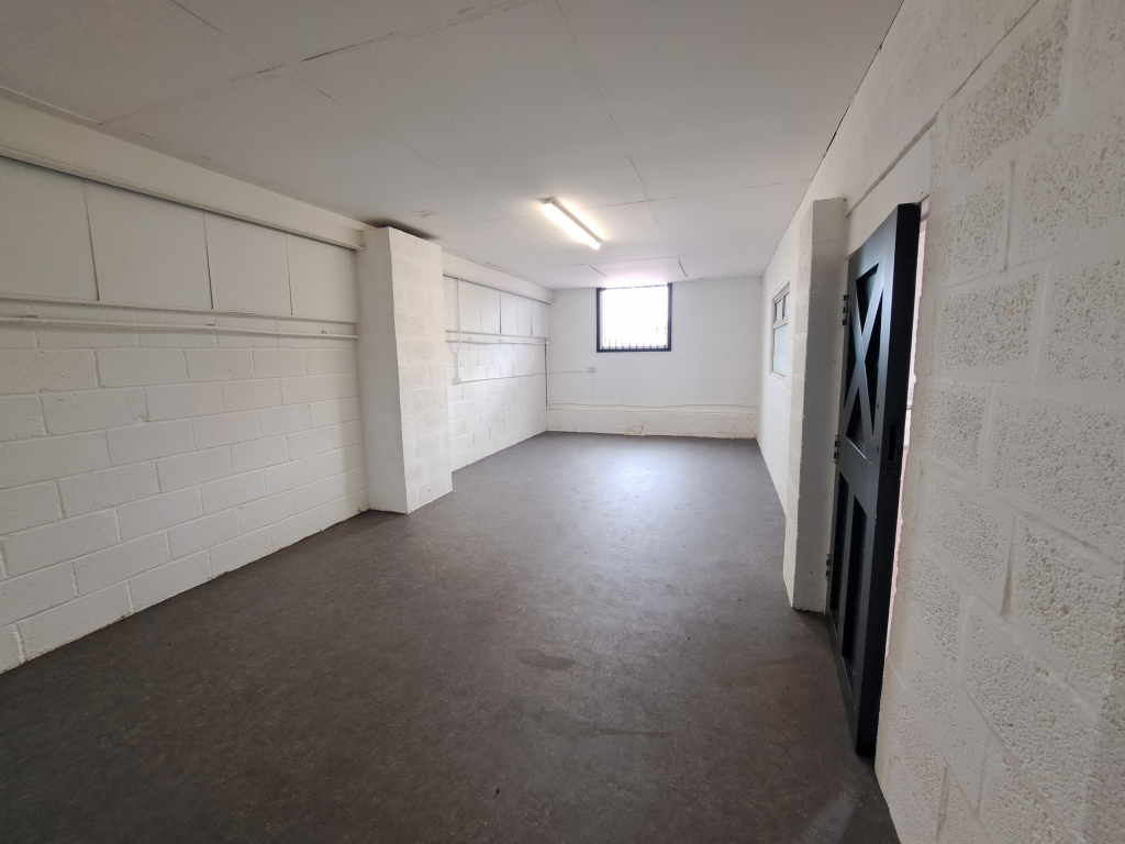 The interior of a warehouse unit, facing the front electric roller shutter, which is closed and large enough for vehicle access.