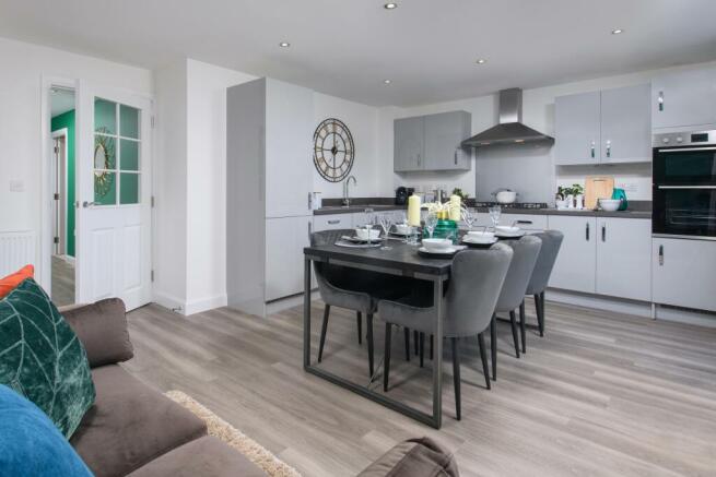 Open-plan kitchen/diner with integrated appliances and French doors leading onto garden in Ingleby s