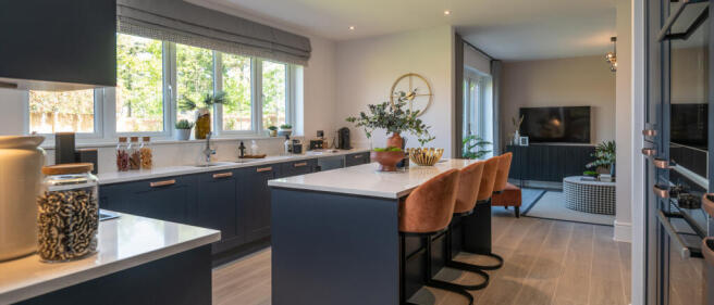 Modern kitchen with navy blue cabinets, white countertops, and warm orange bar stools, adjacent to a