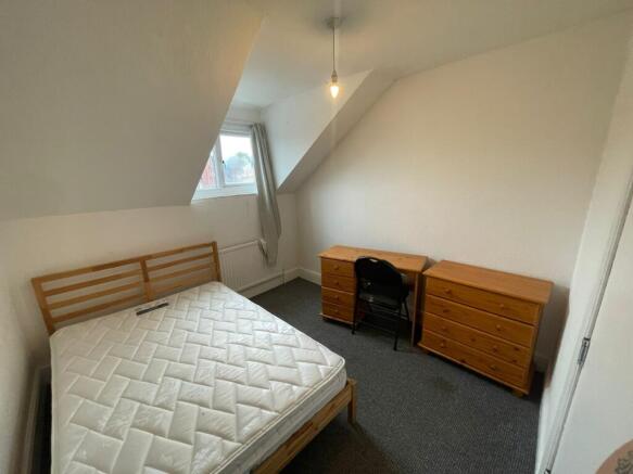 A spacious and bright double bedroom with a des...