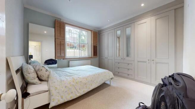 A bright double bedroom featuring a large bed w...