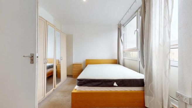 A bright double bedroom featuring a large windo...