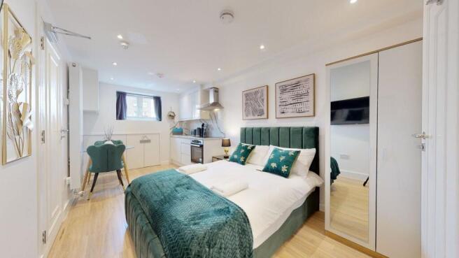 A stylish master bedroom featuring a plush gree...