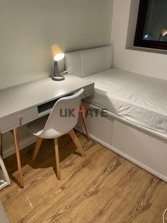 A cozy single bedroom featuring a simple bed, a...