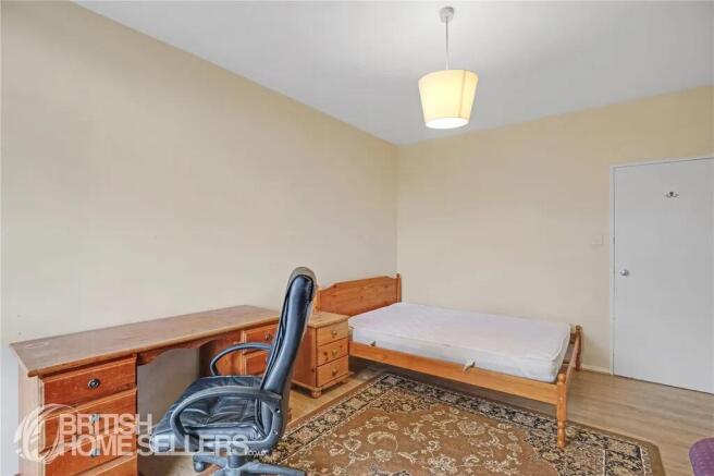 Simple single bedroom featuring a wooden bed fr...