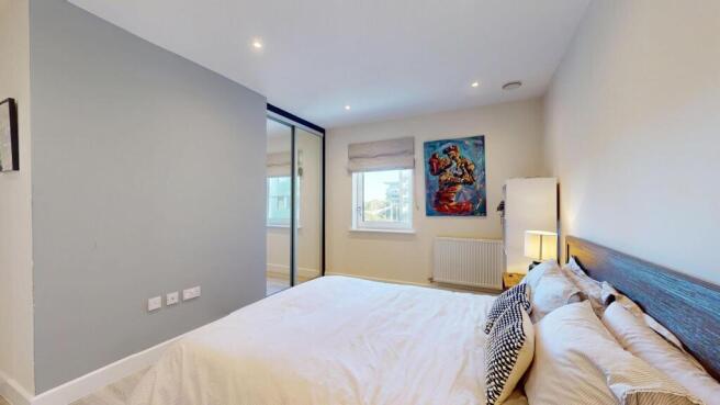A spacious master bedroom featuring a comfortab...