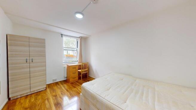 A bright, clean double bedroom featuring a comf...
