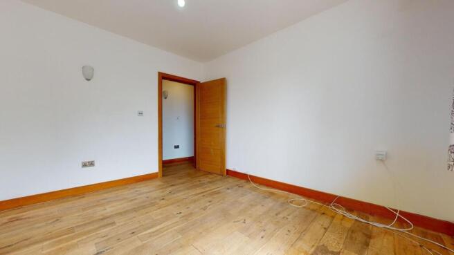 A bright, unfurnished bedroom with wooden floor...
