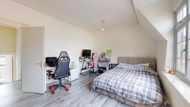 A bright and spacious bedroom featuring a comfo...