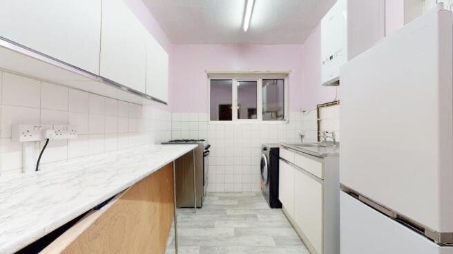 Bright galley kitchen with white cabinets, marb...
