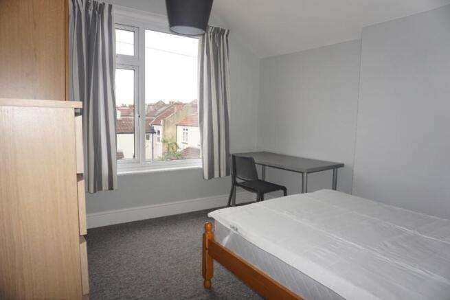 A bright and tidy double bedroom with a desk an...