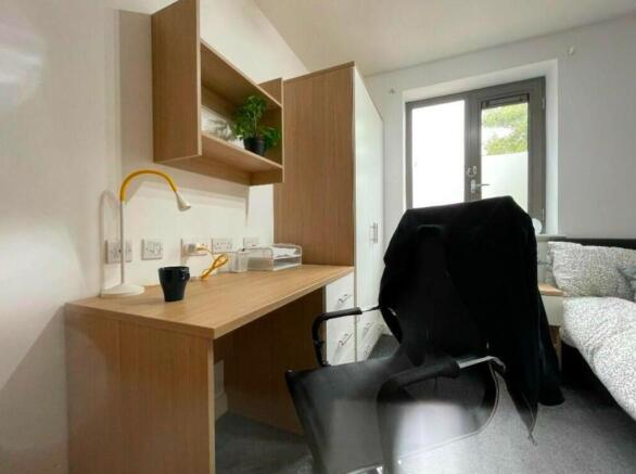 A well-furnished double bedroom with a cozy des...