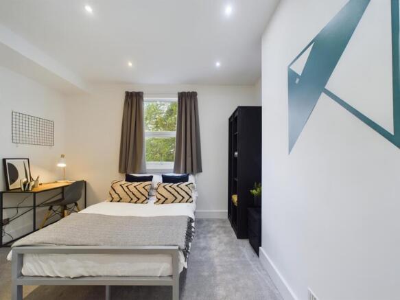 A spacious and well-lit double bedroom with mod...