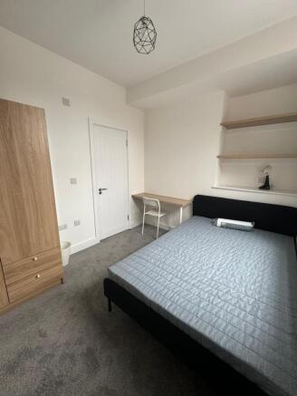 A spacious and tidy double bedroom featuring a ...