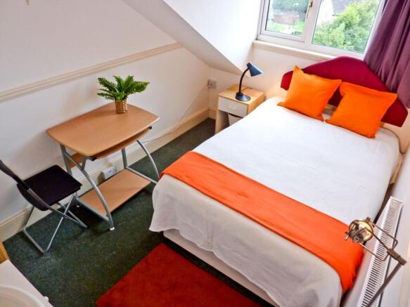 A cozy double bedroom featuring vibrant orange ...