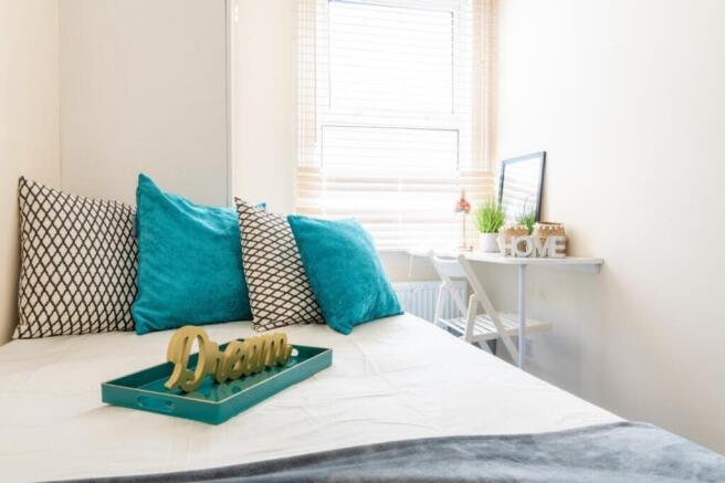 This cozy double bedroom features vibrant teal ...