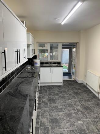 Spacious kitchen featuring sleek black countert...