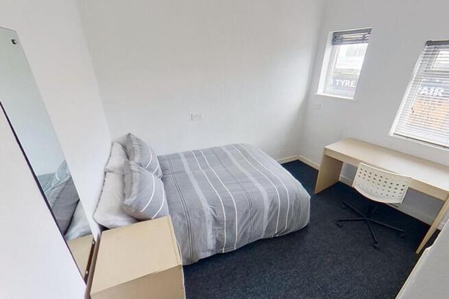 This spacious double bedroom features a comfort...