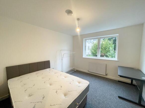 This spacious double bedroom features a comfort...