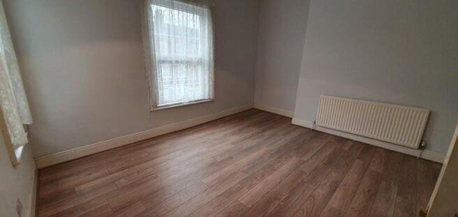 This spacious double bedroom features warm wood...