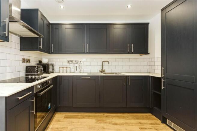 Modern kitchen featuring sleek dark cabinetry a...