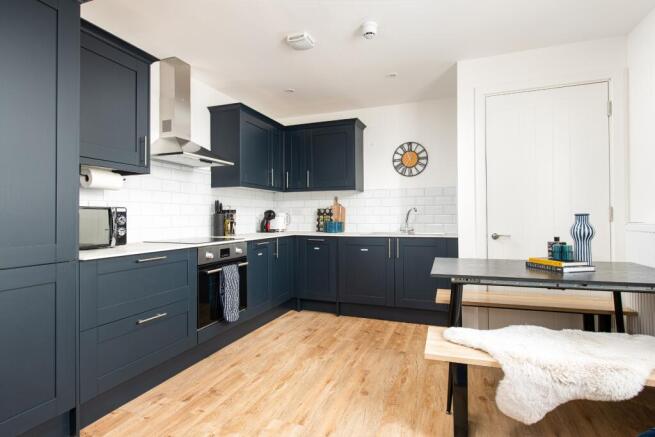 This modern kitchen features sleek dark cabinet...