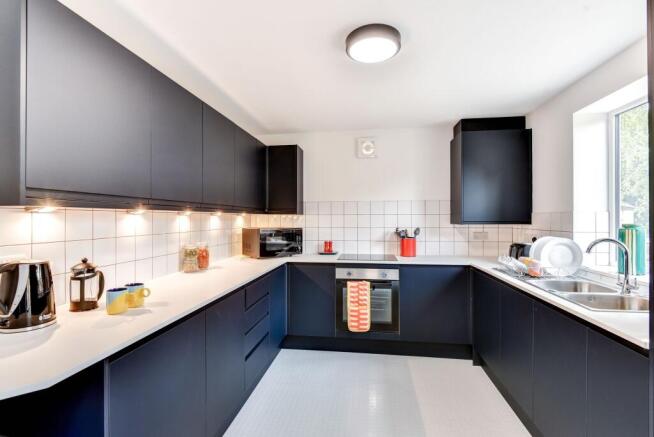 Modern kitchen featuring sleek black cabinetry,...