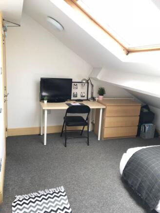This cozy double bedroom features ample natural...