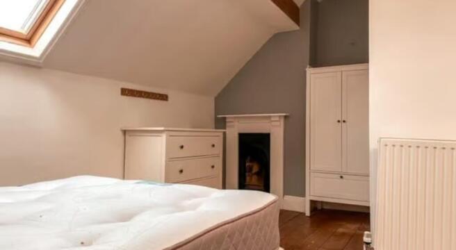 A cozy double bedroom featuring a bright skylig...