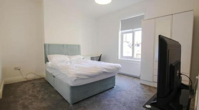 A bright double bedroom featuring a comfortable...