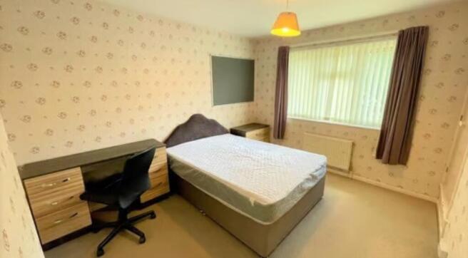 Bright and tidy master bedroom featuring a comf...