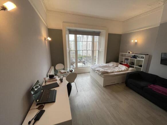A stylish master bedroom featuring a large wind...