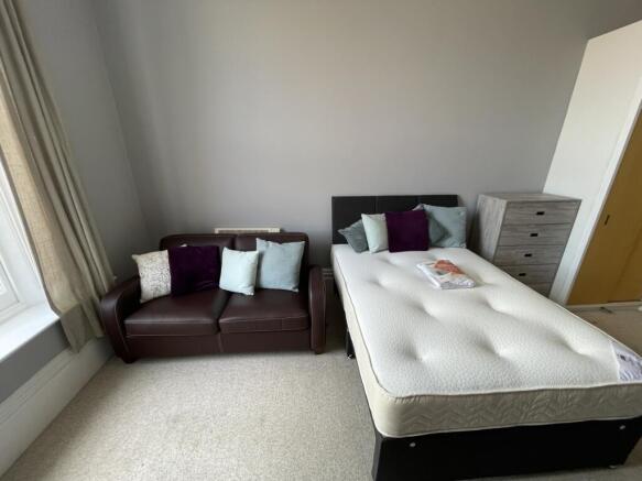 A bright double bedroom featuring a comfortable...