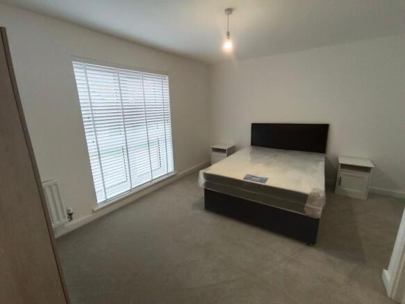 A clean, spacious master bedroom featuring a do...