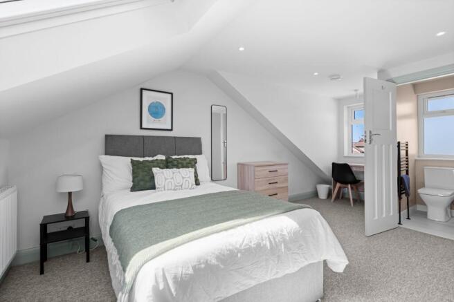 A bright, modern master bedroom featuring a com...