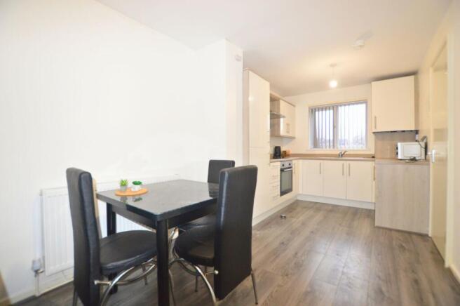 A modern kitchen with light wood laminate floor...